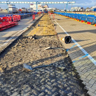 Construction site with uneven ground, equipment, and red safety barriers.