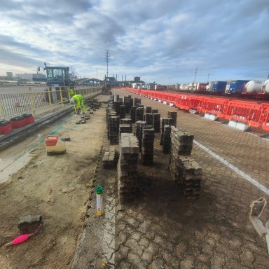 Construction site with stacked bricks and machinery under a cloudy sky.