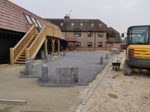 Construction site with a newly paved area, wooden stairs, and machinery in the background.